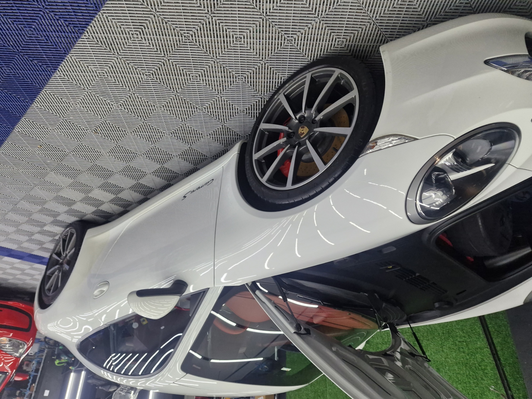 Pistola de pintura automotiva aplicando verniz em uma peça de carro.